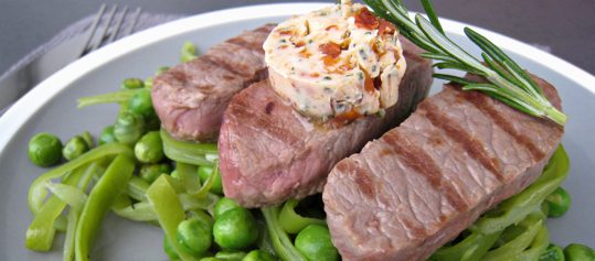 Lammstreifen mit Tomaten-Kräuterbutter auf grünem Gemüse